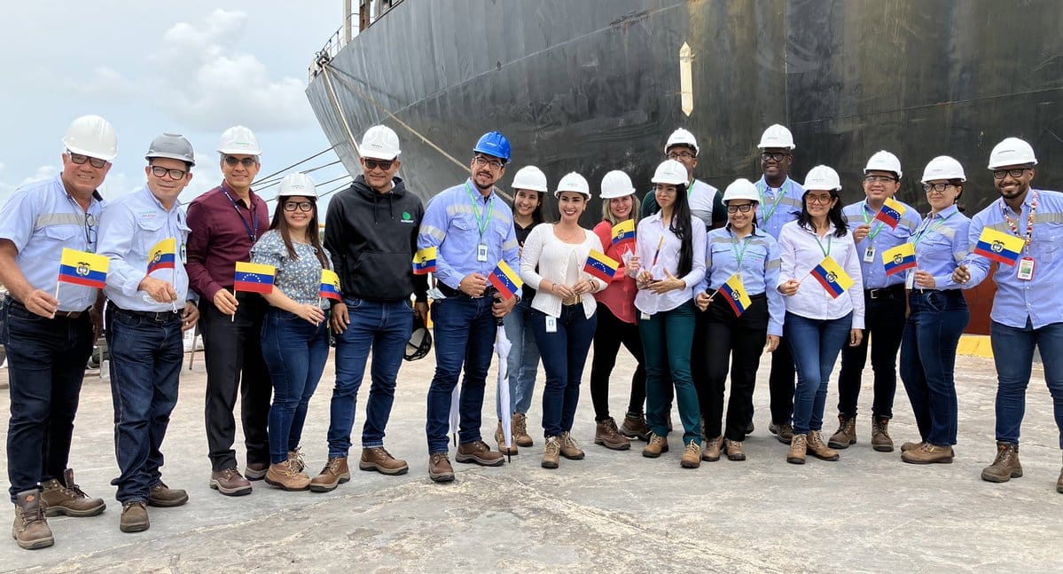 Workers of Pequiven and Monómeros, holding the Venezuelan flag in their hands, stand in front of the first ship that arrived at Monómeros from Venezuela. Photo: Twitter/@monomerossa