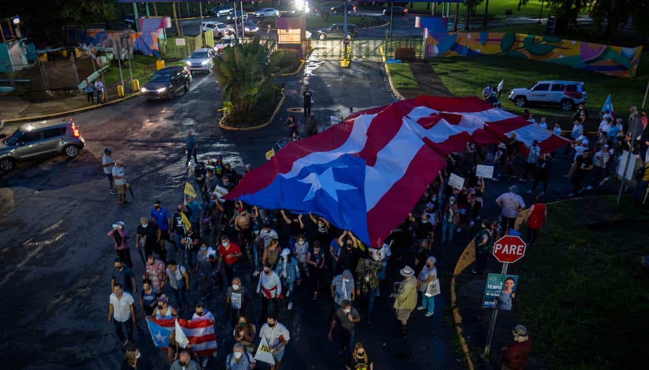 People march along Las Americas Highway as they hold Puerto Rican flags to demand the expulsion of power company Luma amid a continued lack of electricity across the island, in San Juan, Puerto Rico on October 15, 2021. Photo: Ricardo ARDUENGO/AFP via Getty Images.