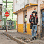 A man walking down a sidewalk in Bogota, Colombia, with a kid climbing on his shoulders. Photo: Alamy.