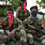 Three ELN fighters, with their faces covered with characteristic red kerchiefs, and holding guns. Photo: Raúl Arboleda/AFP.