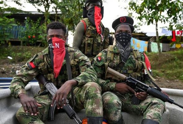 Three ELN fighters, with their faces covered with characteristic red kerchiefs, and holding guns. Photo: Raúl Arboleda/AFP.