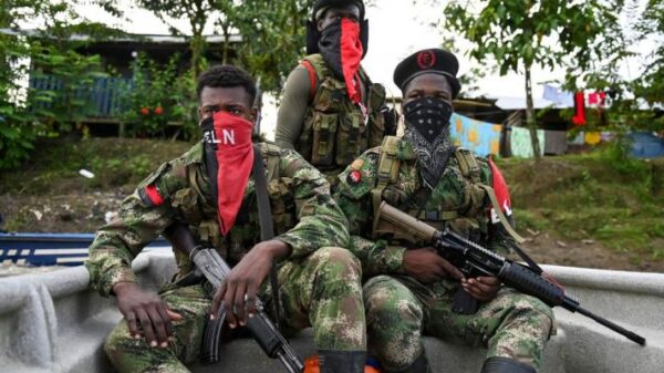 Three ELN fighters, with their faces covered with characteristic red kerchiefs, and holding guns. Photo: Raúl Arboleda/AFP.
