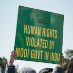 A person holds a sign that reads "Human Rights violated by Modi govt in India". Photo: Gayatri Malhotra.