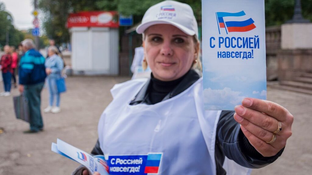 A volunteer hands out pamphlets with the message "With Russia Forever," during the campaign for the referendum to join the Russian Federation, in Lugansk, Ukraine. Photo: EFE.