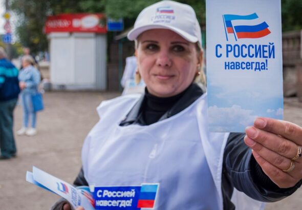 A volunteer hands out pamphlets with the message "With Russia Forever," during the campaign for the referendum to join the Russian Federation, in Lugansk, Ukraine. Photo: EFE.