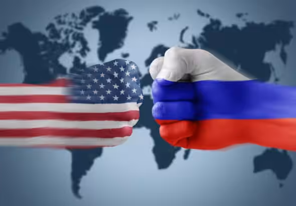 Photo composition of two fists one in front of the other, the one on the left painted with the US flag and the one on the right painted with the Russian flag, and a world map in the background. File photo.