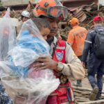 Firefighter holding a rescued child covered in a poncho in Las Tejerias, Aragua state, Venezuela, Sunday, October 9, 2022. Photo: Venezuelan Vice President's Office.