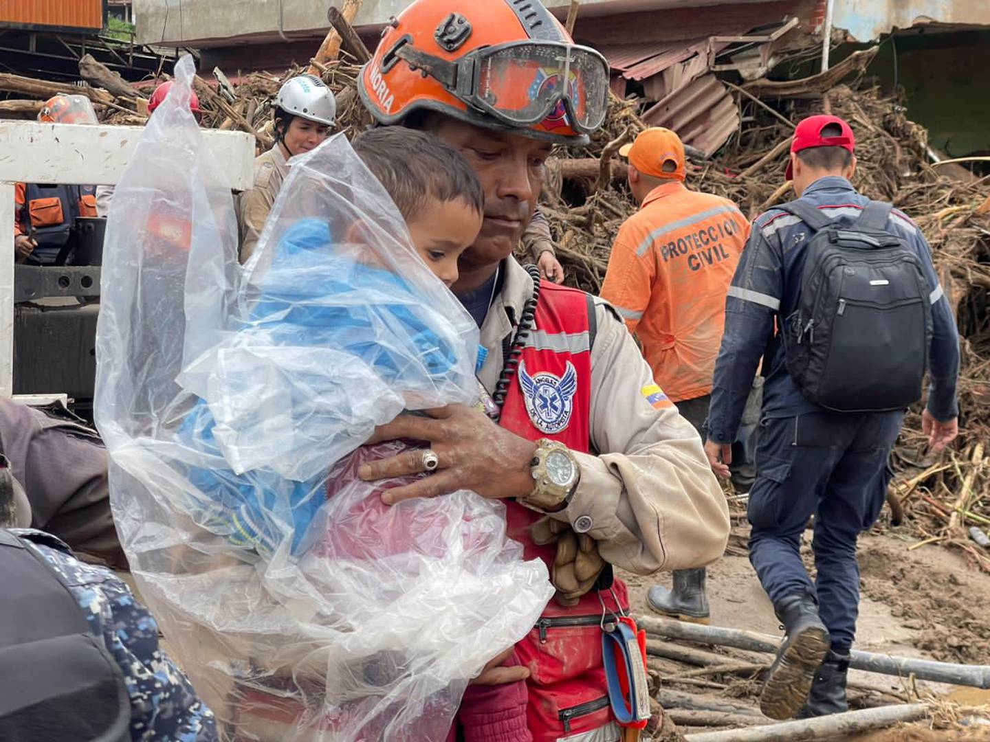 Firefighter holding a rescued child covered in a poncho in Las Tejerias, Aragua state, Venezuela, Sunday, October 9, 2022. Photo: Venezuelan Vice President's Office.