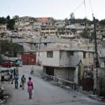 Pleople walking in a Haitian barrio that shows sign of earthquakes destruction. Photo: Colin Crowley – CC BY 2.0