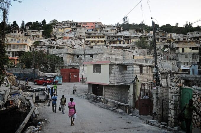 Pleople walking in a Haitian barrio that shows sign of earthquakes destruction. Photo: Colin Crowley – CC BY 2.0