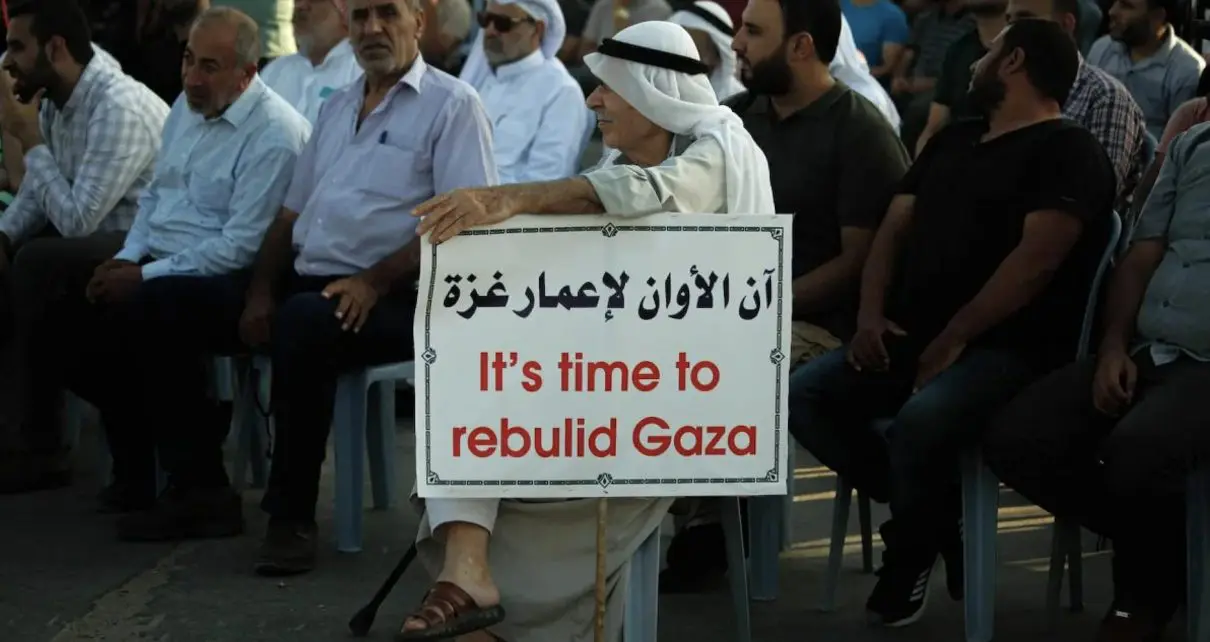 An adult seated at a rally is holding a sign that reads: "it's time to rebel Gaza." Photo: ABACA via Reuters.