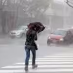 Woman on the street struggling with an umbrella in heavy rain. File photo.
