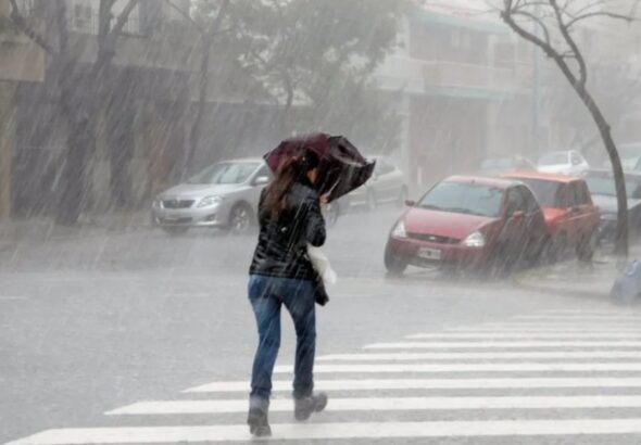 Woman on the street struggling with an umbrella in heavy rain. File photo.