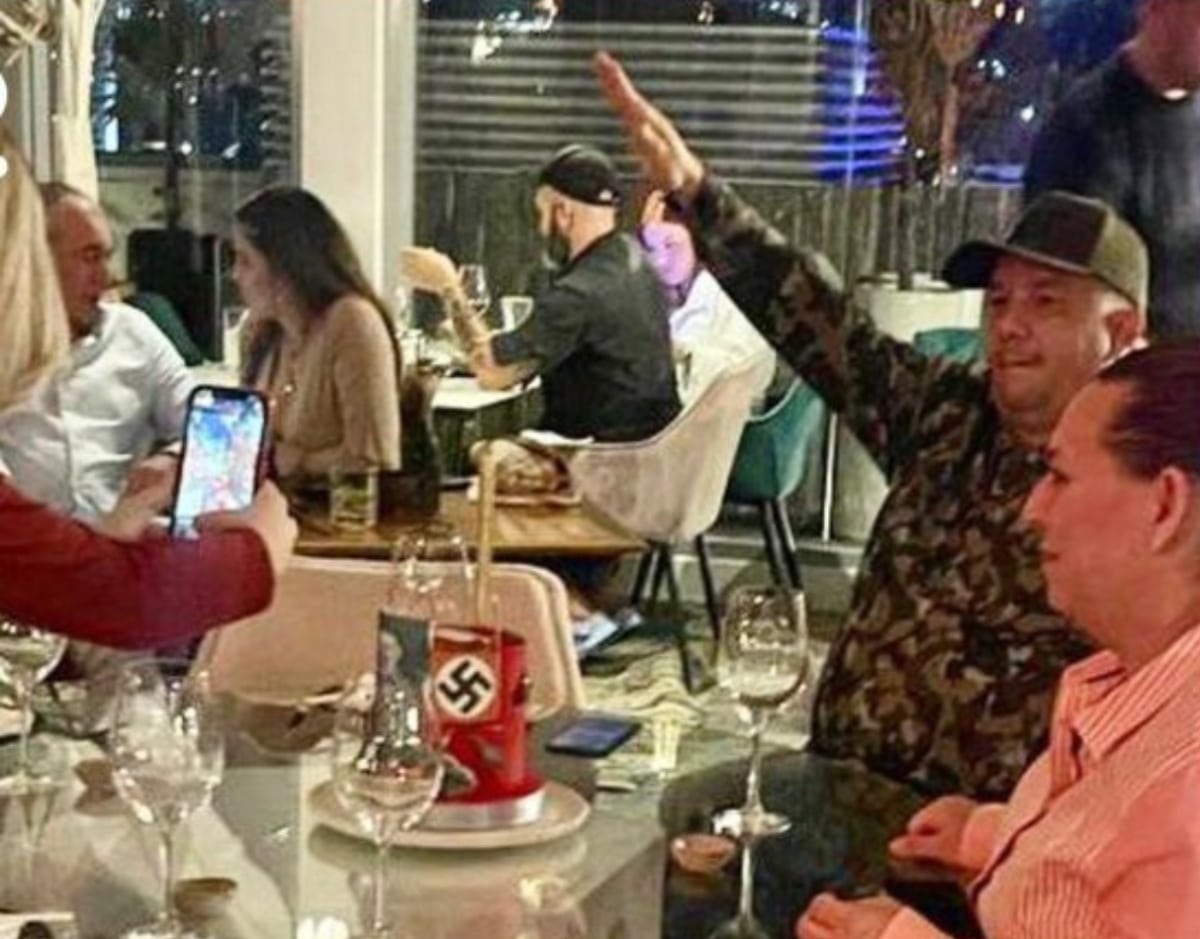 Featured image: A person doing the Nazi salute while being photograph, in front of a birthday cake with Nazi  memorabilia at the Salvaje restaurant in Las Mercedes, Caracas. Photo: Ultimas Noticias.