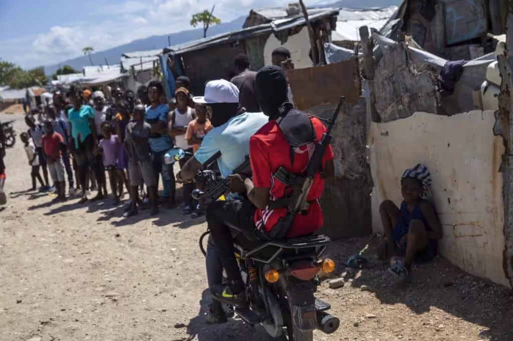 Two armed men ride a motorcycle through the Wharf Jeremy street market in Port-au-Prince, Haiti. Photo: Rodrigo Abd.