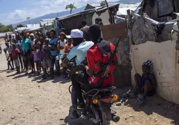 Two armed men ride a motorcycle through the Wharf Jeremy street market in Port-au-Prince, Haiti. Photo: Rodrigo Abd.