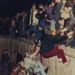 East Berliners climb atop the Berlin Wall with the help of West Berliners in the early morning hours of Nov. 10, 1989. Photo: Jockel Finck AP.