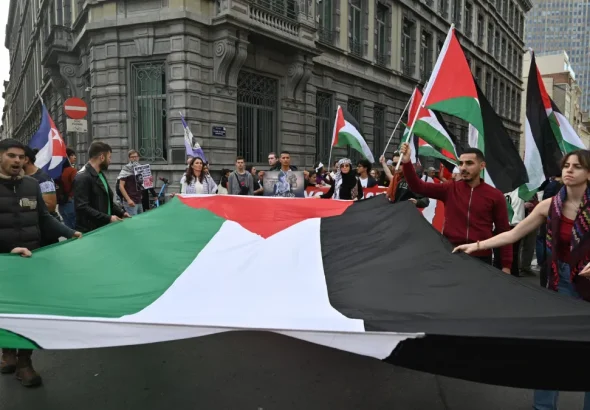 People marching and holding a big flag. Photo: Masar Badil.