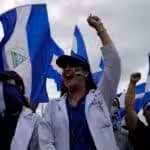 Doctors raise their fist triumphantly grasping the Nicaraguan flag. Photo: The Lancet
