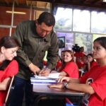 President Hugo Chavez autographing a book for the students of Mission Sucre. File photo.