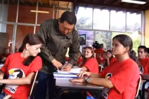 President Hugo Chavez autographing a book for the students of Mission Sucre. File photo.