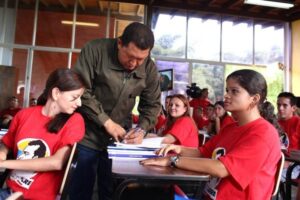 President Hugo Chavez autographing a book for the students of Mission Sucre. File photo.