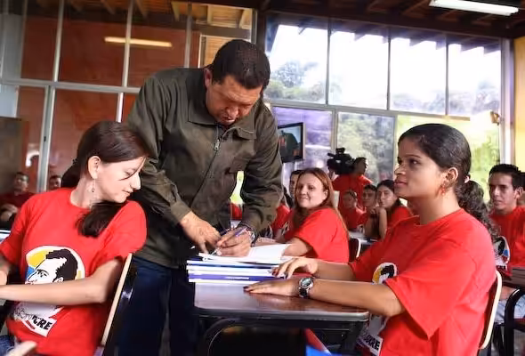 President Hugo Chavez autographing a book for the students of Mission Sucre. File photo.
