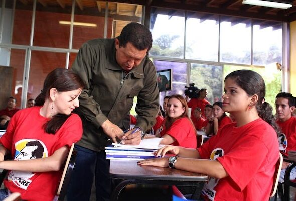 President Hugo Chavez autographing a book for the students of Mission Sucre. File photo.