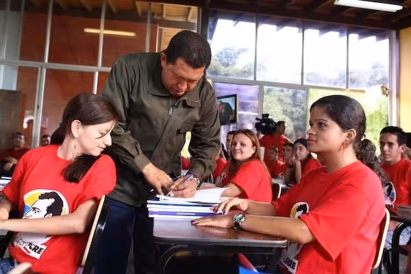President Hugo Chavez autographing a book for the students of Mission Sucre. File photo.
