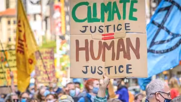 Person in a demonstration holding a banner that reads "Climate Justice equals Human Justice". File photo.
