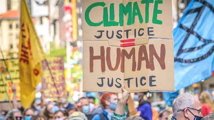Person in a demonstration holding a banner that reads "Climate Justice equals Human Justice". File photo.