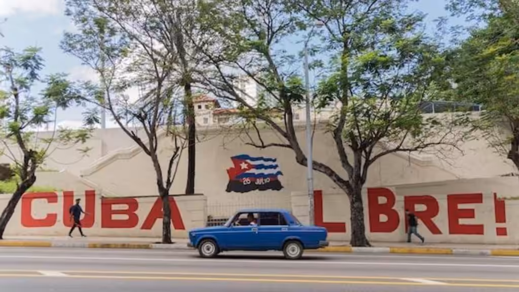 A person and a driver passing by a graffiti that says "Cuba Libre". Photo: Yerson Olivares.