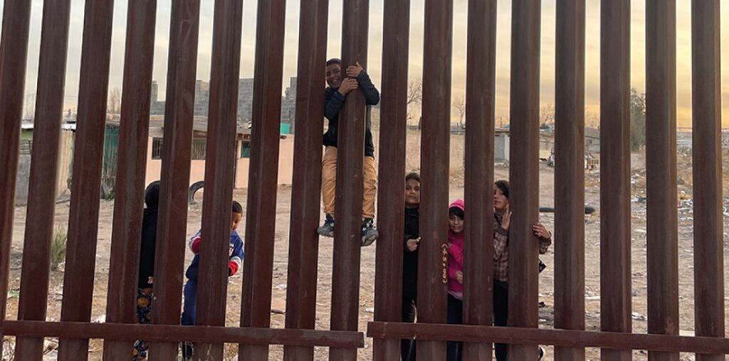 Children play by the fence on the Mexican side of the US-Mexico border in the desert scrub. File photo.
