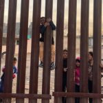 Children play by the fence on the Mexican side of the US-Mexico border in the desert scrub. File photo.