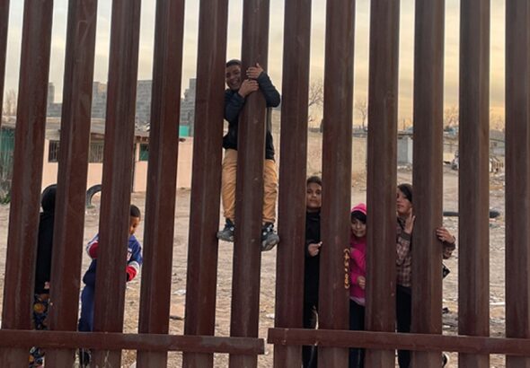 Children play by the fence on the Mexican side of the US-Mexico border in the desert scrub. File photo.