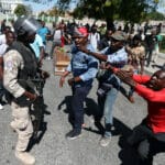 Local residents argue with a policeman while the casket of a man, shot dead during anti-government protests, lies on the ground in Port-au-Prince, Haiti, February 22, 2019. Photo: Ivan Alvarado/Reuters.