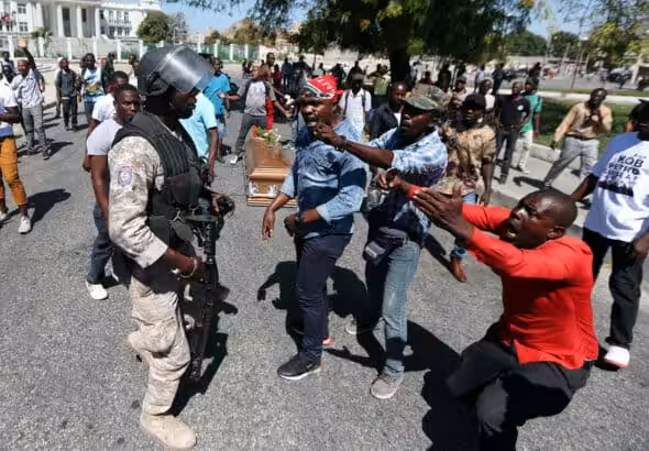 Local residents argue with a policeman while the casket of a man, shot dead during anti-government protests, lies on the ground in Port-au-Prince, Haiti, February 22, 2019. Photo: Ivan Alvarado/Reuters.