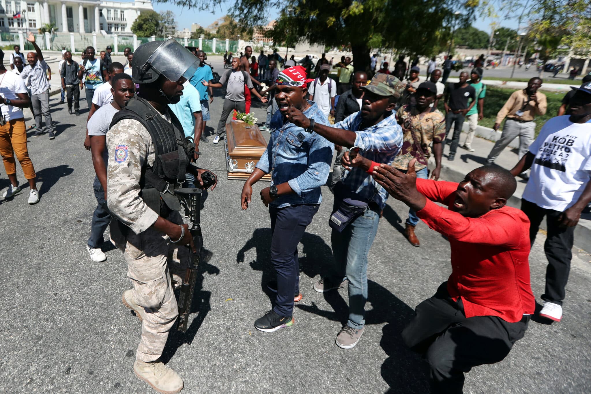 Local residents argue with a policeman while the casket of a man, shot dead during anti-government protests, lies on the ground in Port-au-Prince, Haiti, February 22, 2019. Photo: Ivan Alvarado/Reuters.