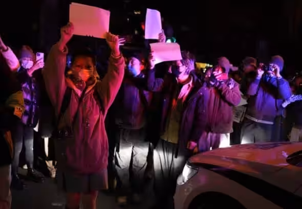 Protesters hold up blank papers and chant slogans as they march in protest in Beijing, Sunday, November 27, 2022. Photo: Morning Star. 