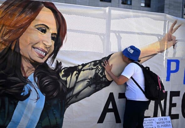 A supporter of Cristina Fernández de Kirchner kisses a banner of the vice-president hung outside the courthouse in Buenos Aires on Tuesday, December 6, 2022. Photo: AFP/Getty Images.