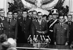 Dictator Jorge Rafael Videla (center) is sworn in as president of the military junta in Argentina in 1976. File photo from Wikimedia Commons.