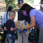 Venezuelan Vice President Delcy Rodríguez (right) hands a Christmas gift to a boy in Las Tejerías. Photo: Twitter/@ViceVenezuela.