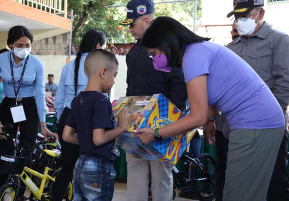 Venezuelan Vice President Delcy Rodríguez (right) hands a Christmas gift to a boy in Las Tejerías. Photo: Twitter/@ViceVenezuela.