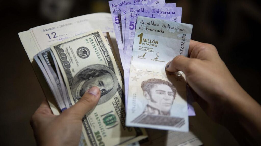 A person holds bolívar notes in one hand and US dollar bills in the the other. File photo.