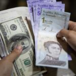 A person holds bolívar notes in one hand and US dollar bills in the the other. File photo.
