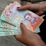 A woman holding bolivar notes in downtown Caracas. Photo: Federico Parra for Getty Images.