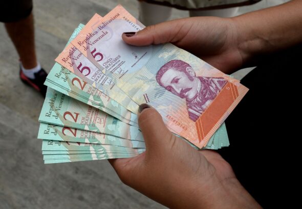 A woman holding bolivar notes in downtown Caracas. Photo: Federico Parra for Getty Images.