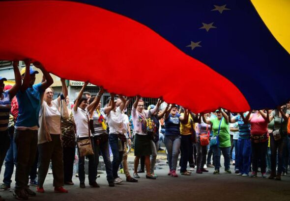Protestors hold up large Venezuelan flag. Photo: Archive.