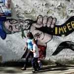 A woman and a girl walk in front of a graffiti of US Uncle Sam in Caracas on March 11, 2015. Photo: AFP/Federico Parra/Getty Images.