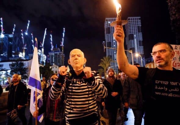 A man wears handcuffs and a mask depicting Israeli prime minister Benjamin Netanyahu, as he takes part in a protest against Netanyahu's new right-wing cabinet and its proposed judicial reforms in Tel Aviv, the occupied territories, on January 14, 2023. Photo: Reuters.